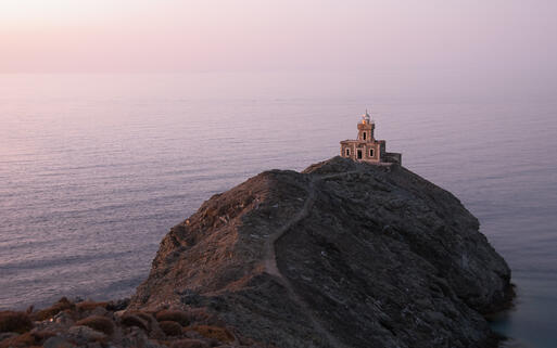 Ein Leuchtturm thront auf der Felsküste von Tinos © YK / Shutterstock.com