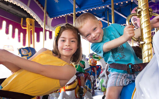 Kinder bei einer Karussellfahrt in einem Themenpark © Brocreative / Shutterstock.com